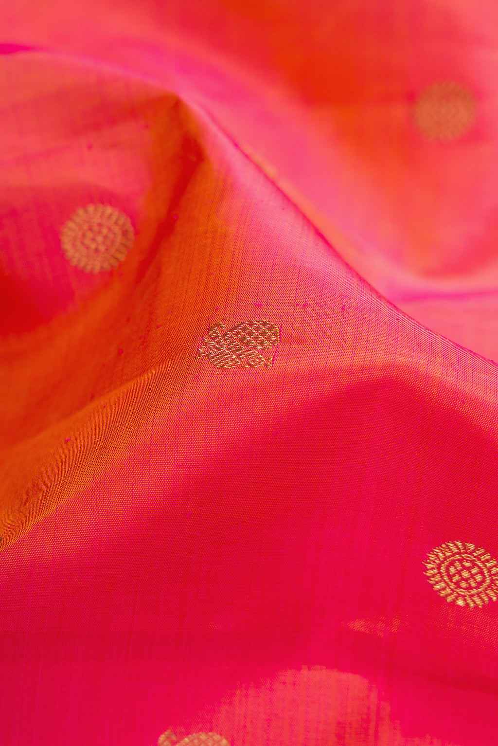 Close up of Pure Silk Pure Zari Coral Dual Tone Kanjivaram Saree with Zari Butta on the body and Zari Border.  displaying folds