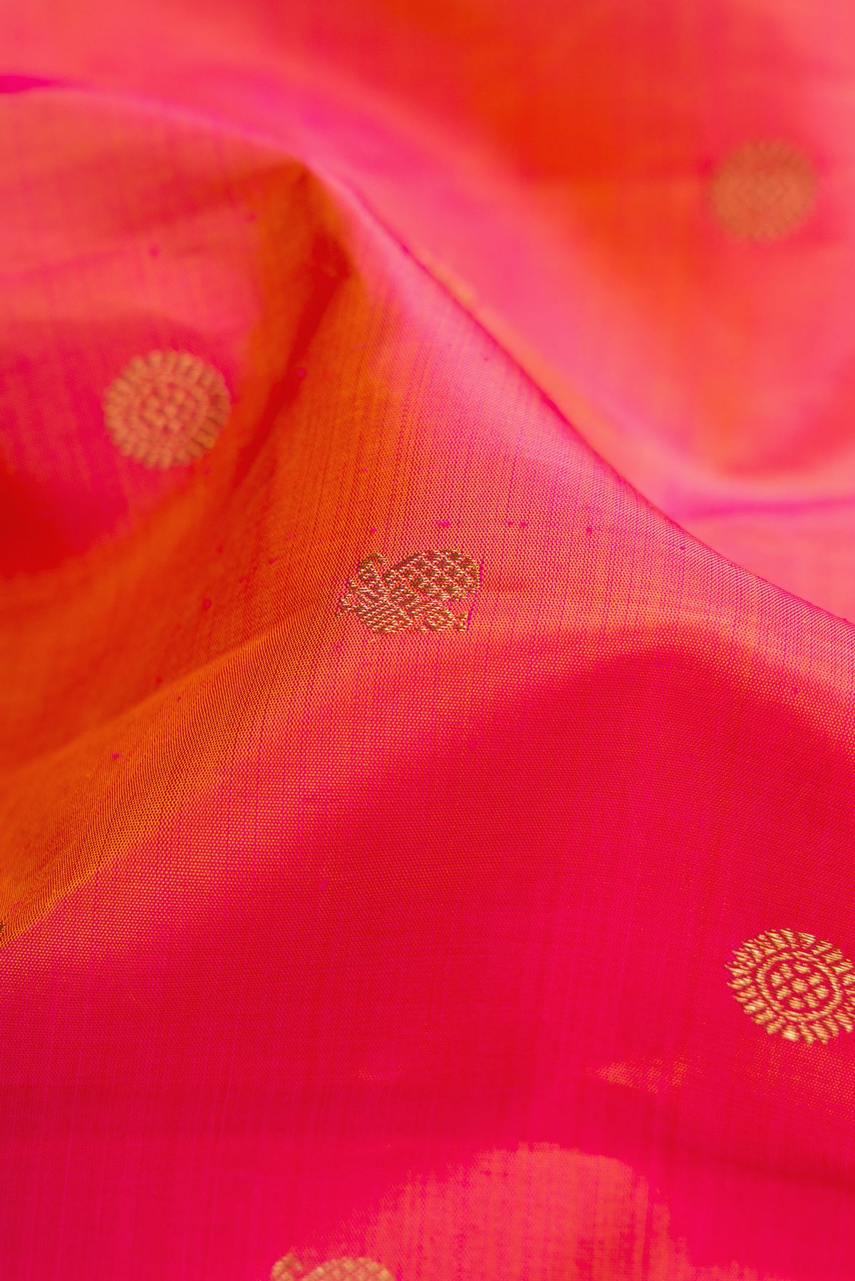 Close up of Pure Silk Pure Zari Coral Dual Tone Kanjivaram Saree with Zari Butta on the body and Zari Border.  displaying folds
