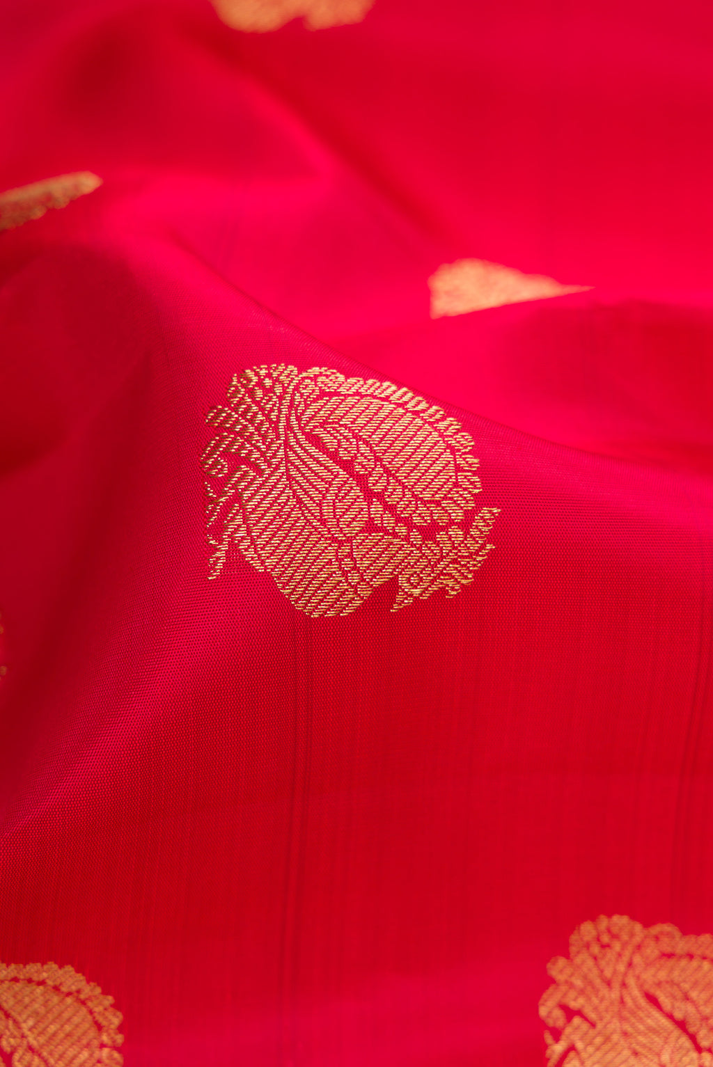 Close up of Pure Silk Pure Zari Red Dual Tone Kanjivaram Saree with Zari Butta on the body and Zari Border.  displaying folds