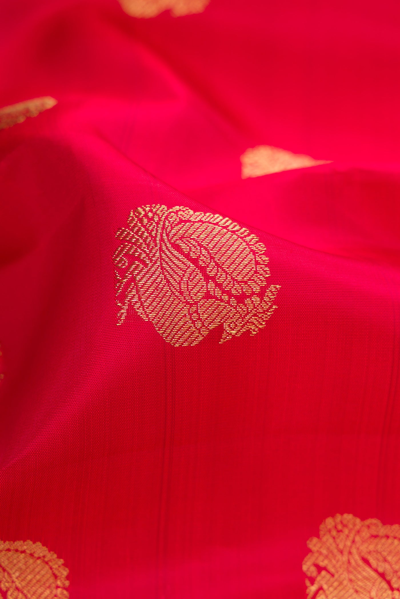 Close up of Pure Silk Pure Zari Red Dual Tone Kanjivaram Saree with Zari Butta on the body and Zari Border.  displaying folds