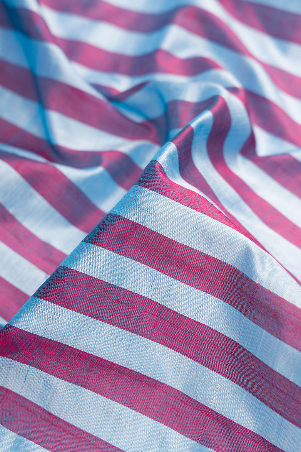Close up of Blue and Maroon Color Kanchipuram Silk Saree with Stripes on the body and Zari Border.  displaying folds