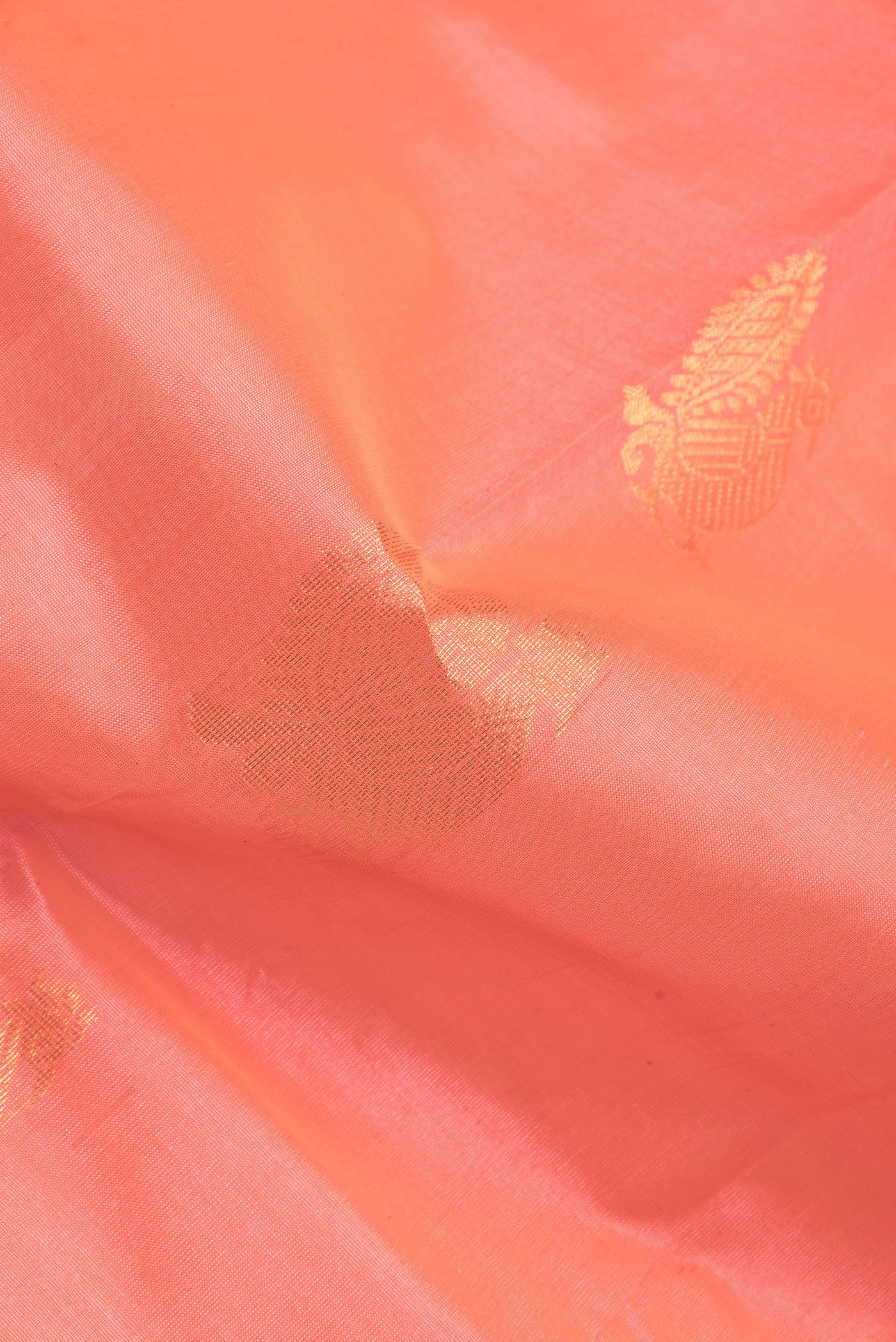 Close up of Peach Dual Tone Silk Cotton Saree with Zari Butta on the body and Zari Border.  displaying folds