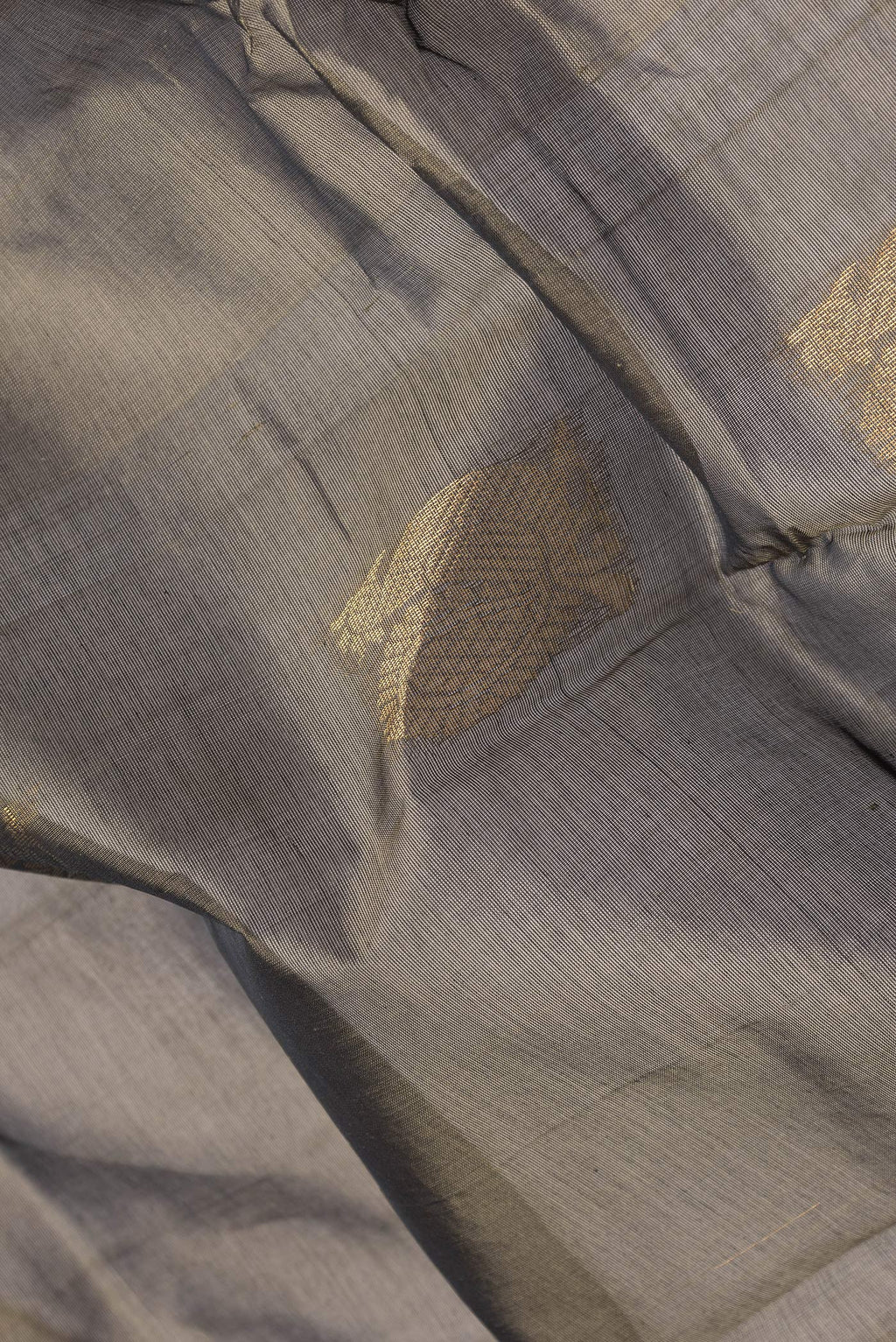 Close up of Grey Silk Cotton Saree with Zari Butta on the body and Zari Border.  displaying folds