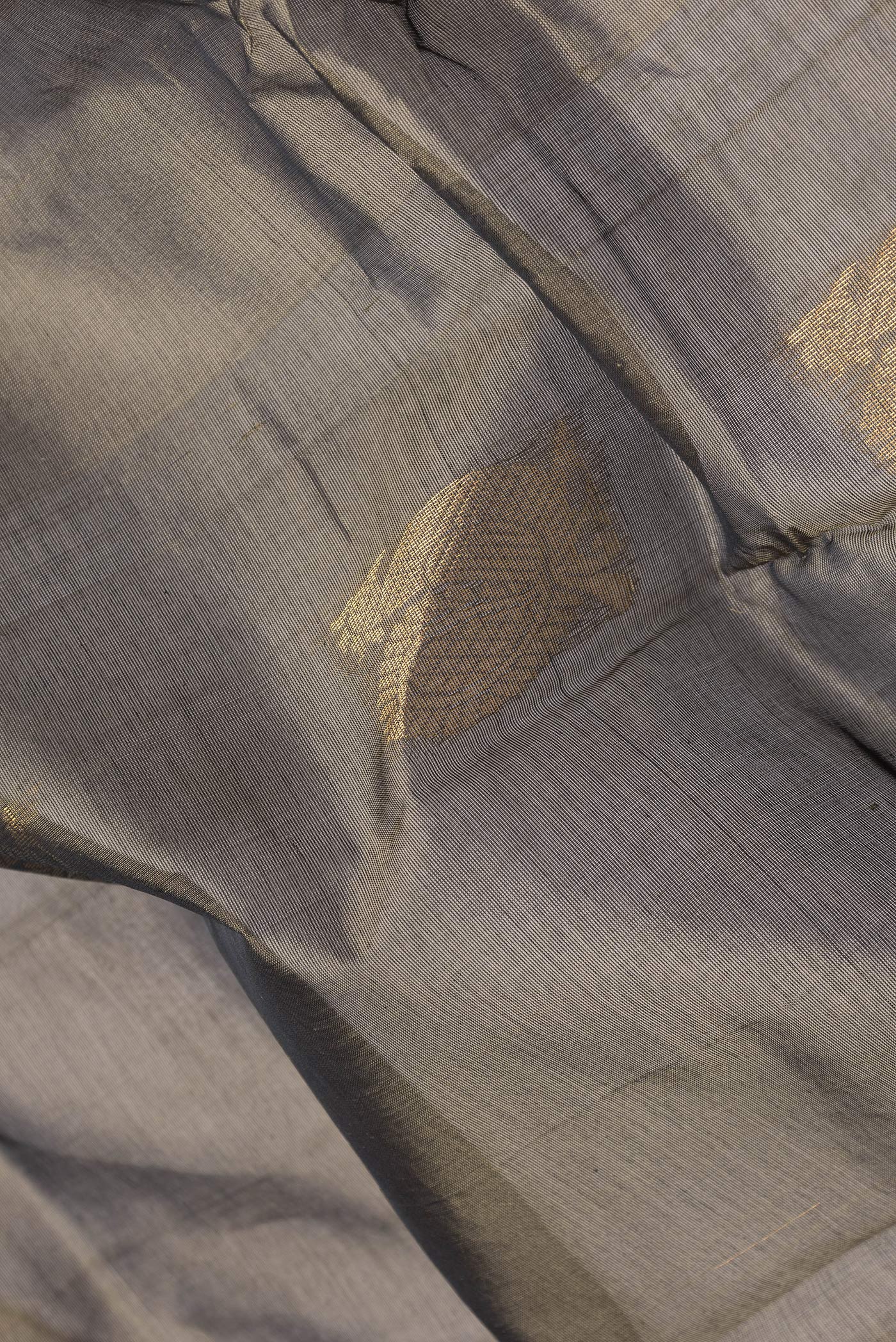 Close up of Grey Silk Cotton Saree with Zari Butta on the body and Zari Border.  displaying folds