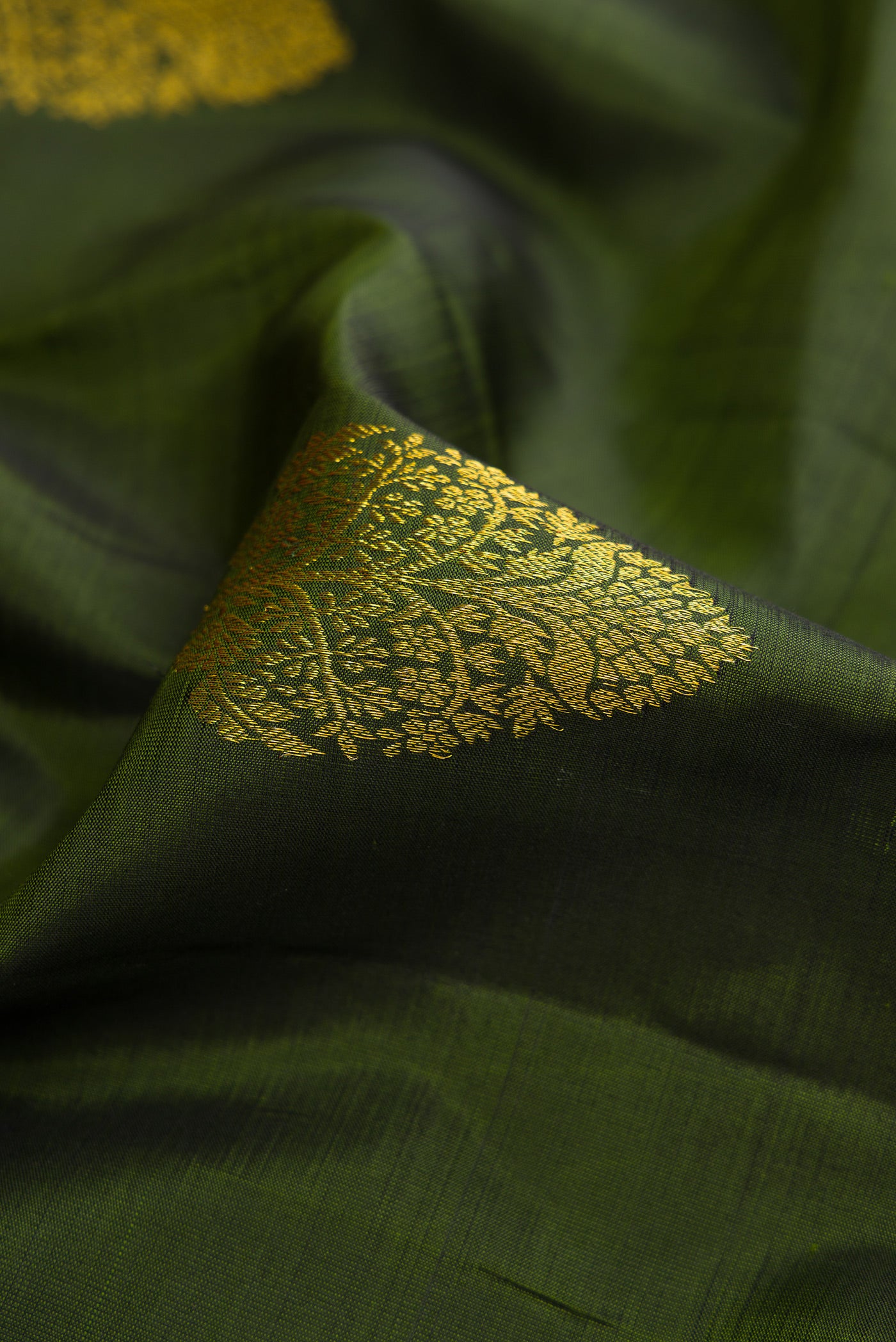 Close up of Mehandi Green Dual Tone Kanjivaram Silk Saree with Zari Butta on the body and Zari Border.  displaying folds