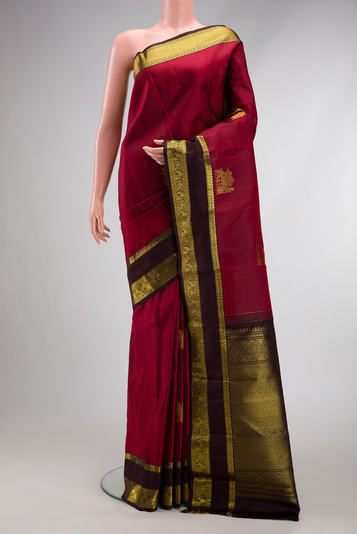 Maroon Kanjivaram Silk Saree with Zari Butta on the body and Zari Border.  displayed on a mannequin