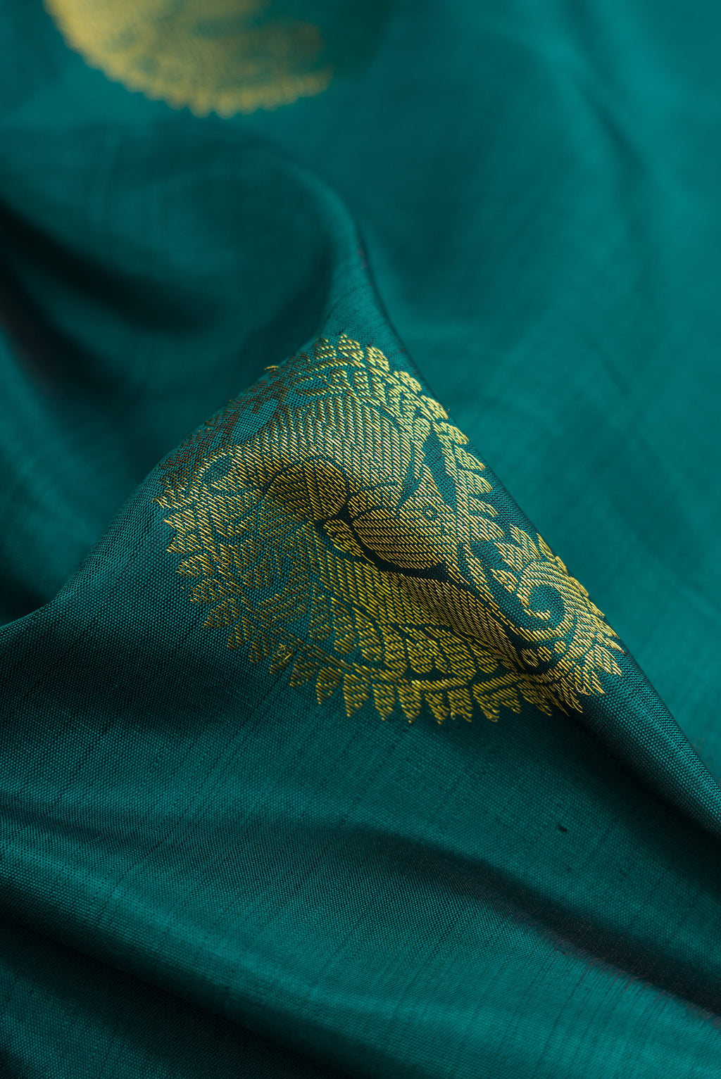 Close up of Green Dual Tone Kanjivaram Silk Saree with Zari Butta on the body and Zari Border.  displaying folds