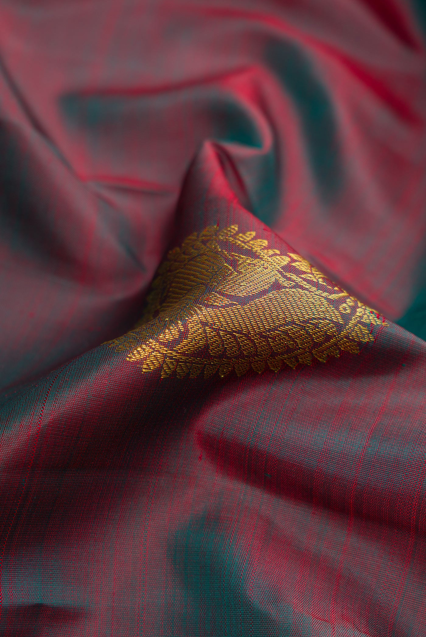 Close up of Mehandi Green Dual Tone Kanjivaram Silk Saree with Zari Butta on the body and Zari Border.  displaying folds