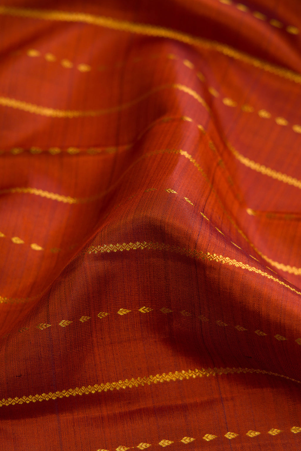 Close up of Brick Orange Dual Tone Kanjivaram Silk Saree with Stripes on the body and Zari Border.  displaying folds