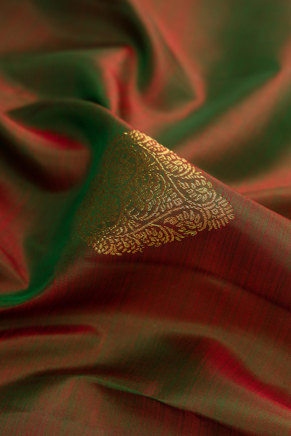 Close up of Mehandi Green Dual Tone Kanjivaram Silk Saree with Zari Butta on the body and Zari Border.  displaying folds