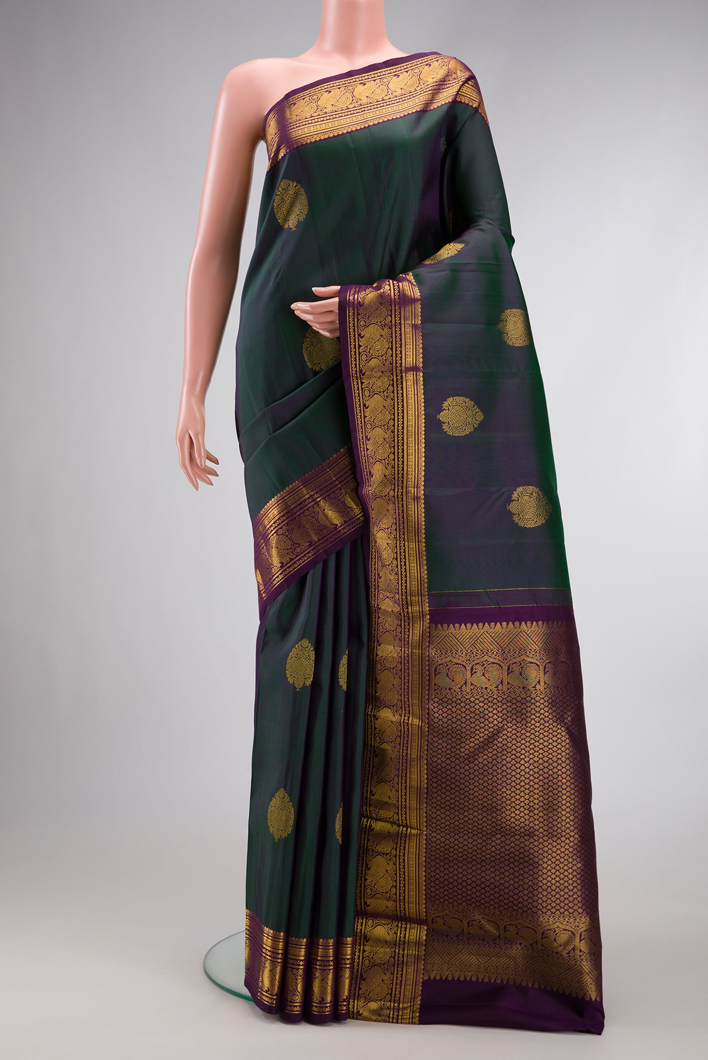 Bottle Green Dual Tone Kanjivaram Silk Saree with Zari Butta on the body and Zari Border.  displayed on a mannequin