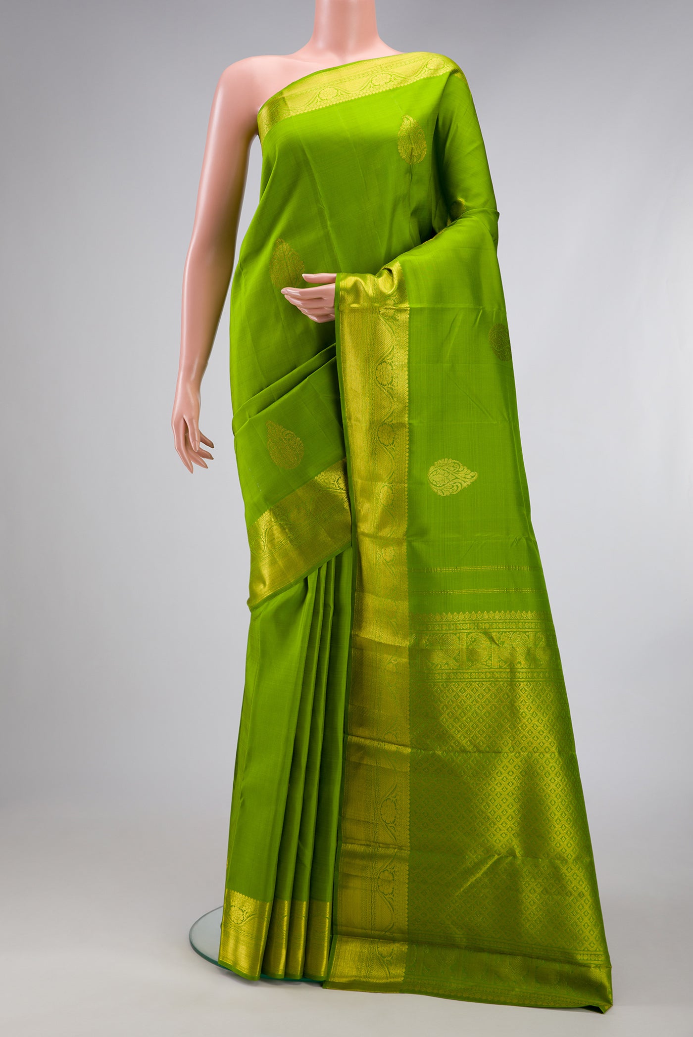 Parrot Green Kanjivaram Silk Saree with Zari Butta on the body and Zari Border.  displayed on a mannequin
