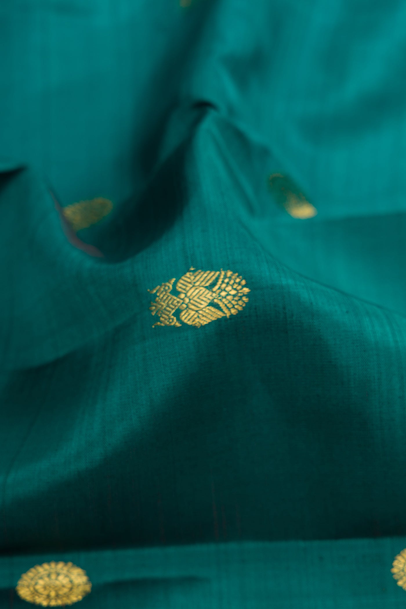 Close up of Green Dual Tone Kanjivaram Silk Saree with Zari Butta on the body and Zari Border.  displaying folds