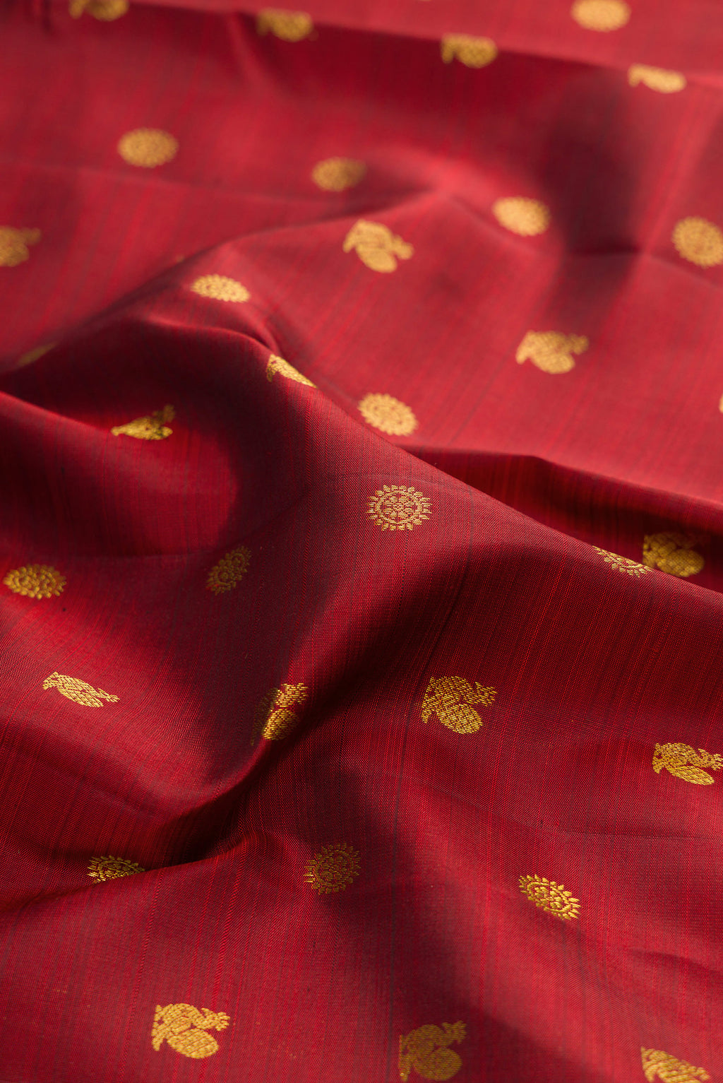 Close up of Maroon Kanjivaram Silk Saree with Zari Butta on the body and Zari Border.  displaying folds