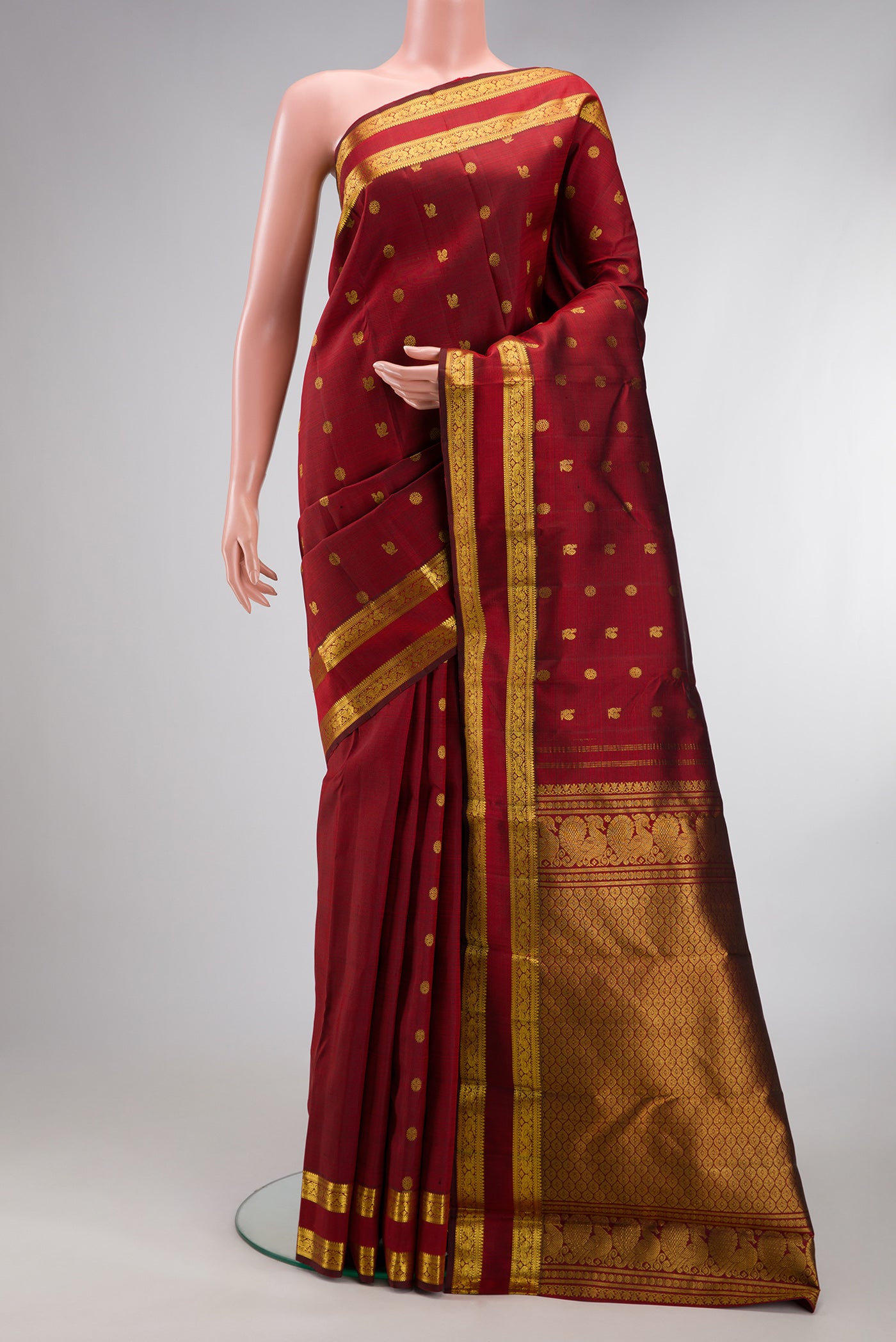 Maroon Kanjivaram Silk Saree with Zari Butta on the body and Zari Border.  displayed on a mannequin