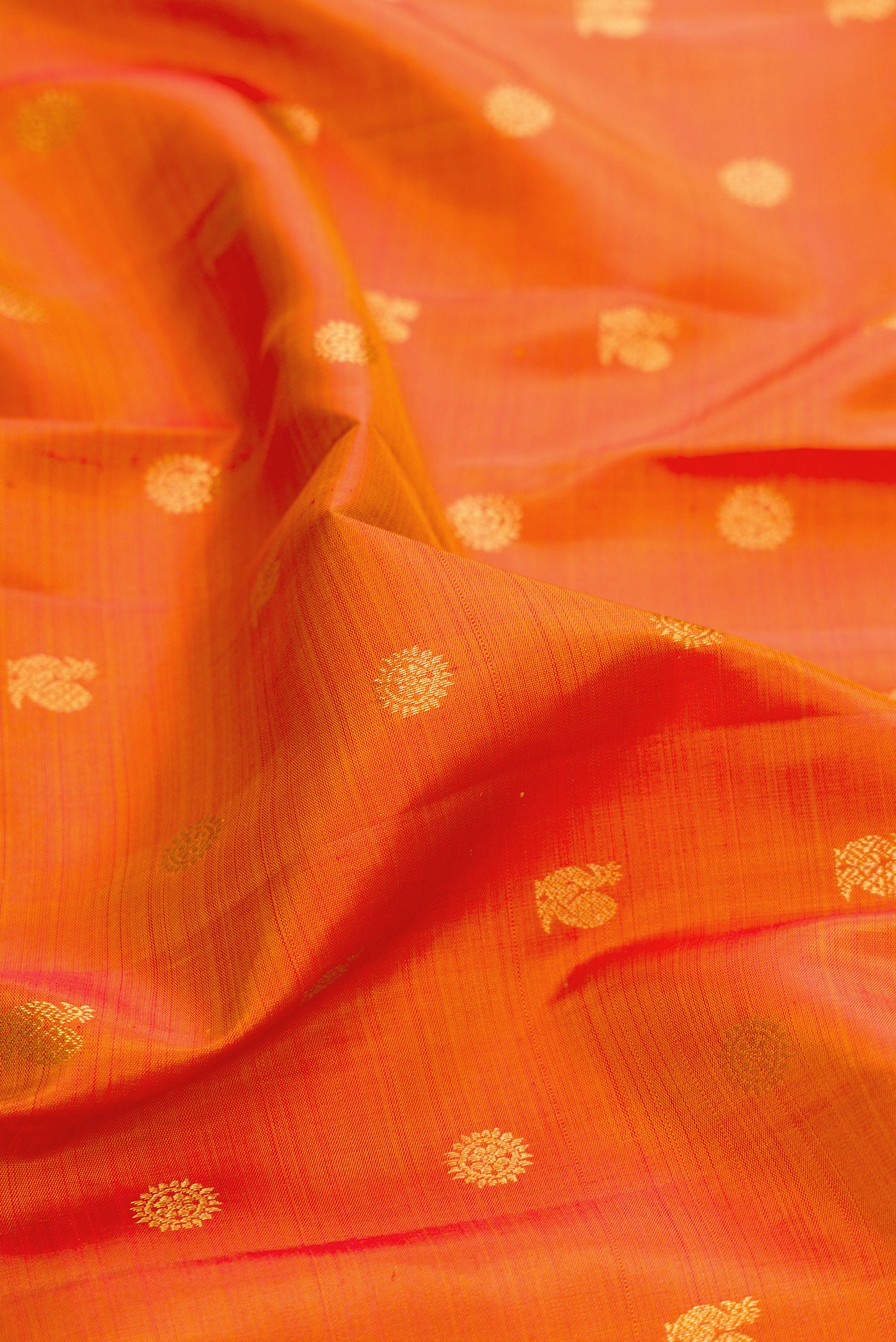 Close up of Orange Dual Tone Kanjivaram Silk Saree with Zari Butta on the body and Zari Border.  displaying folds