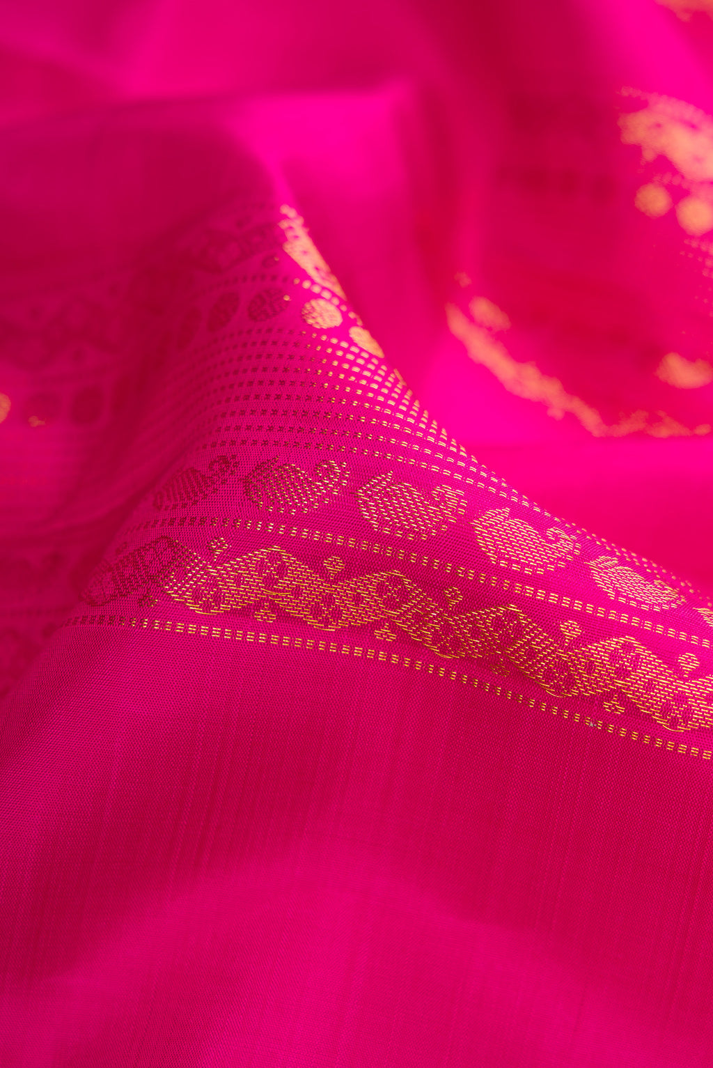 Close up of Dark Pink Kanjivaram Silk Saree with Zari Butta on the body and Without Border.  displaying folds