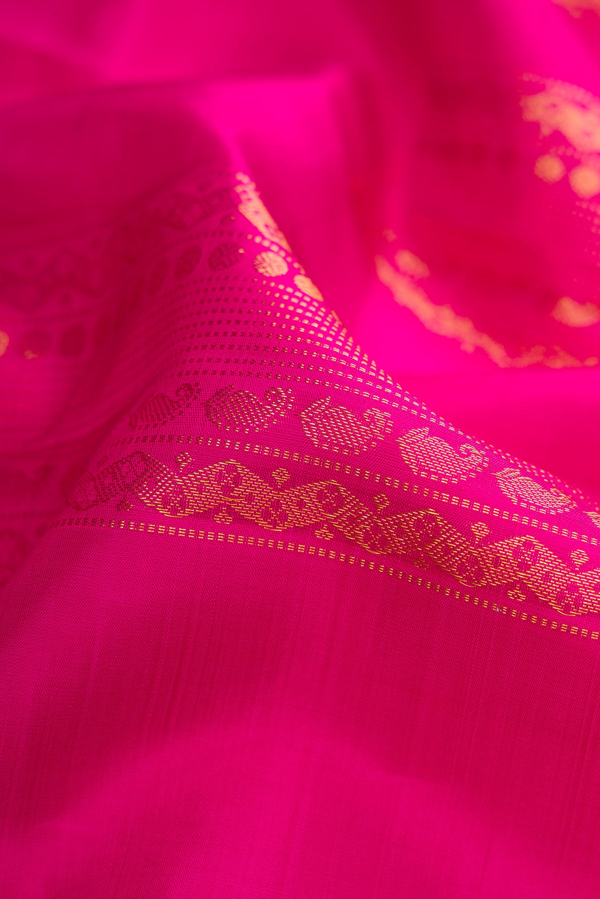 Close up of Dark Pink Kanjivaram Silk Saree with Zari Butta on the body and Without Border.  displaying folds