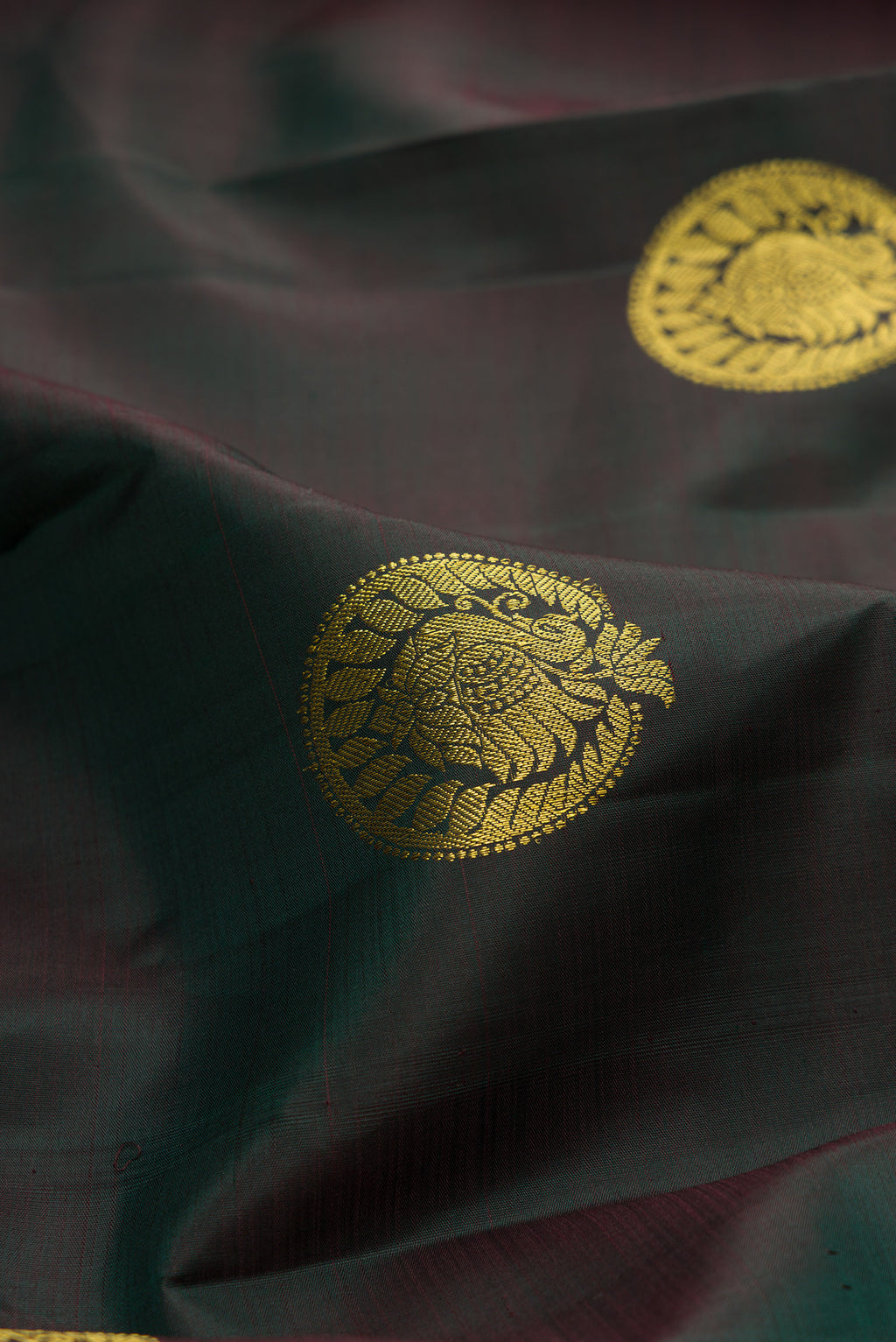 Close up of Bottle Green Dual Tone Kanchipuram Silk Saree with Zari Butta on the body and Zari Border.  displaying folds
