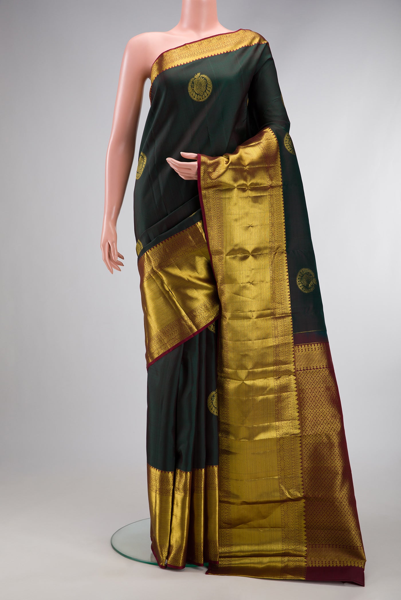 Bottle Green Dual Tone Kanchipuram Silk Saree with Zari Butta on the body and Zari Border.  displayed on a mannequin