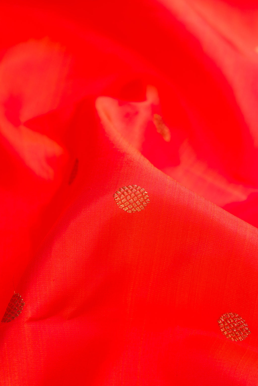 Close up of Pure Silk Pure Zari Orange Dual Tone Kanjivaram Saree with Zari Butta on the body and Zari Border.  displaying folds