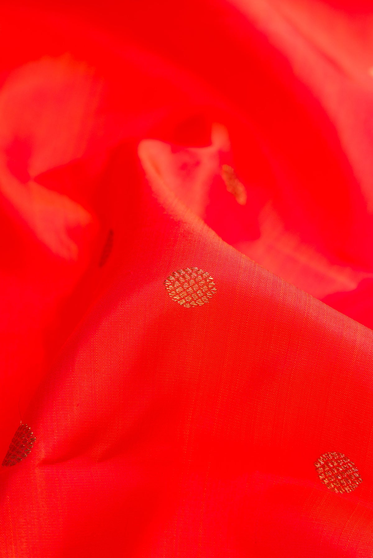Close up of Pure Silk Pure Zari Orange Dual Tone Kanjivaram Saree with Zari Butta on the body and Zari Border.  displaying folds