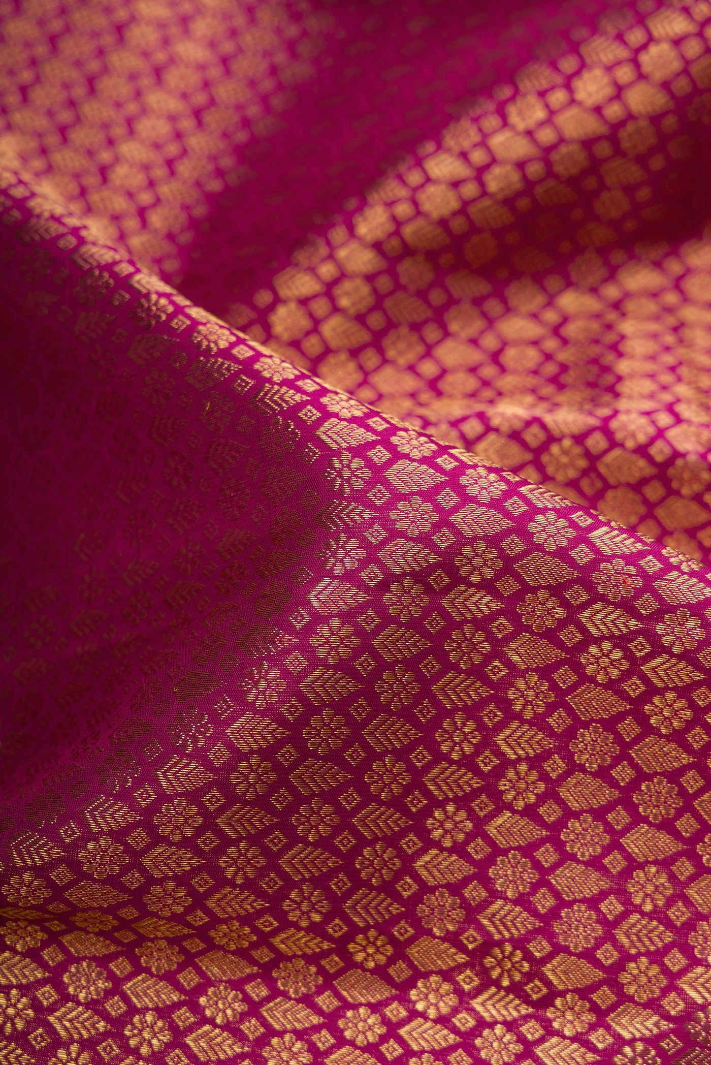 Close up of Pure Silk Pure Zari Magenta Kanjivaram Saree with Zari Brocade on the body and Zari Border.  displaying folds
