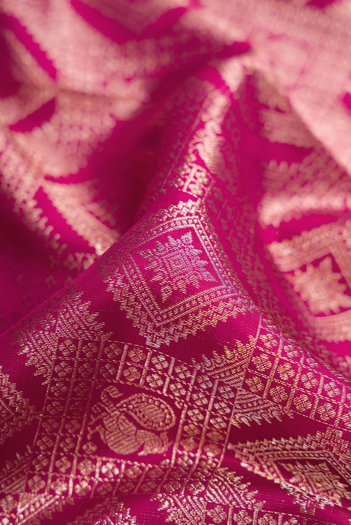 Close up of Magenta Dual Tone Kanchipuram Silk Saree with Zari Brocade on the body and Zari Border.  displaying folds