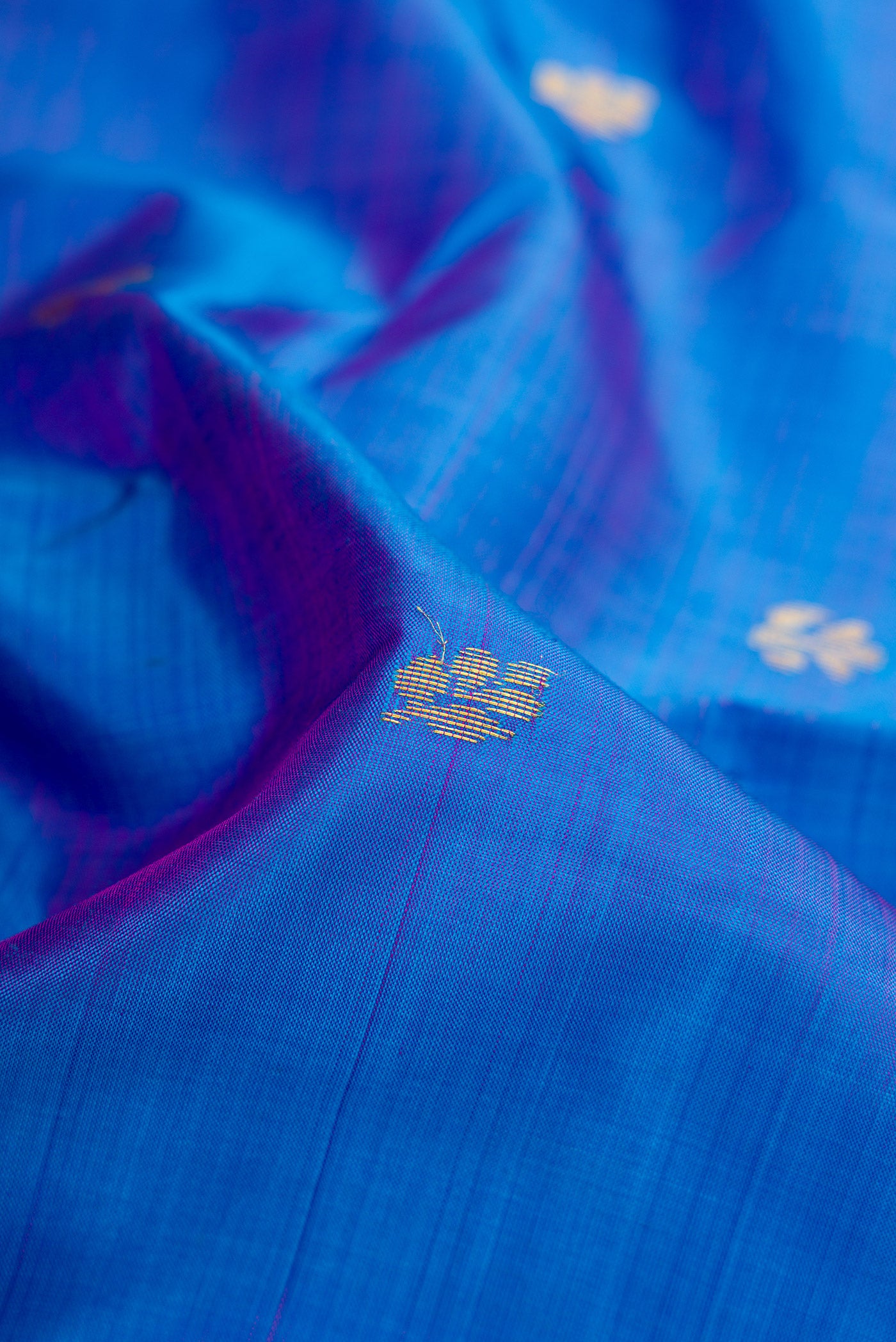 Close up of Peacock Blue Dual Tone Kanjivaram Silk Saree with Zari Butta on the body and Zari Border.  displaying folds