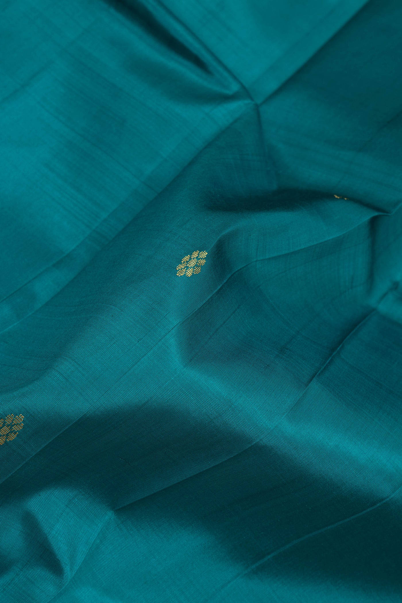 Close up of Peacock Blue Dual Tone Kanjivaram Silk Saree with Zari Butta on the body and One Side Border.  displaying folds