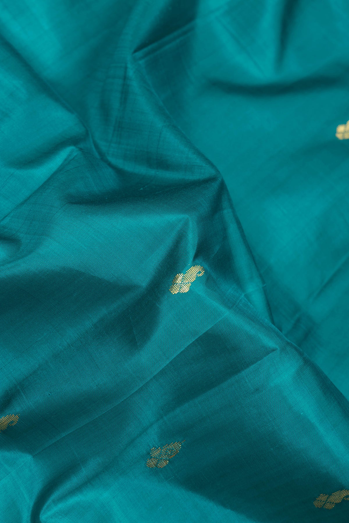 Close up of Peacock Blue Kanjivaram Silk Saree with Zari Butta on the body and One Side Border.  displaying folds