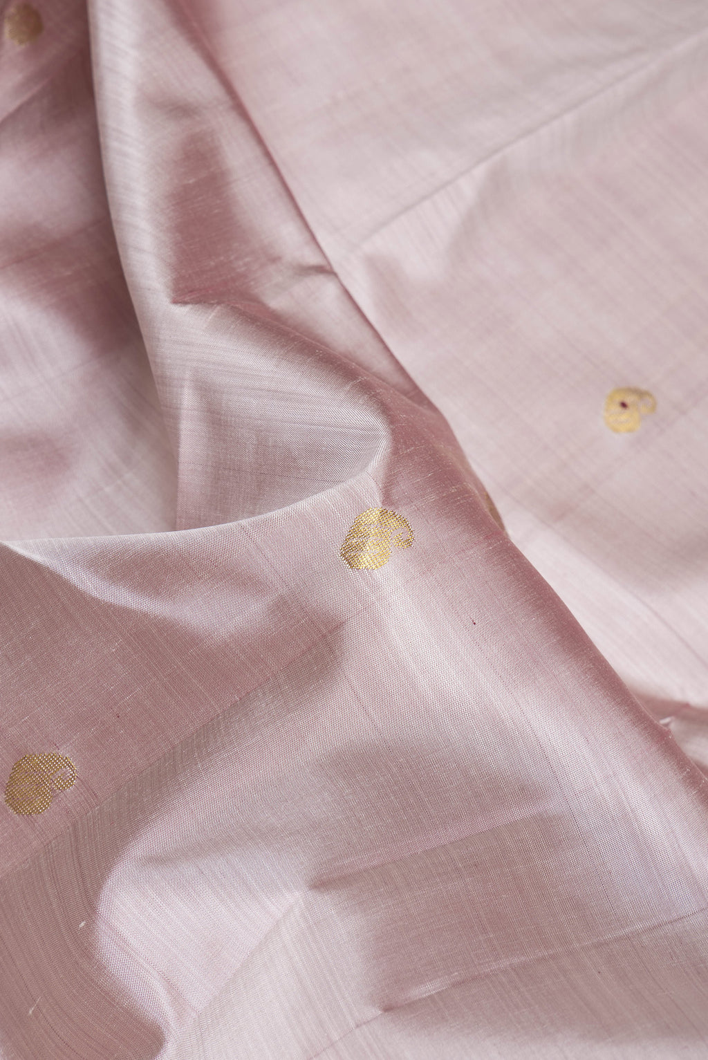 Close up of Rose Gold Dual Tone Kanjivaram Silk Saree with Zari Butta on the body and One Side Border.  displaying folds