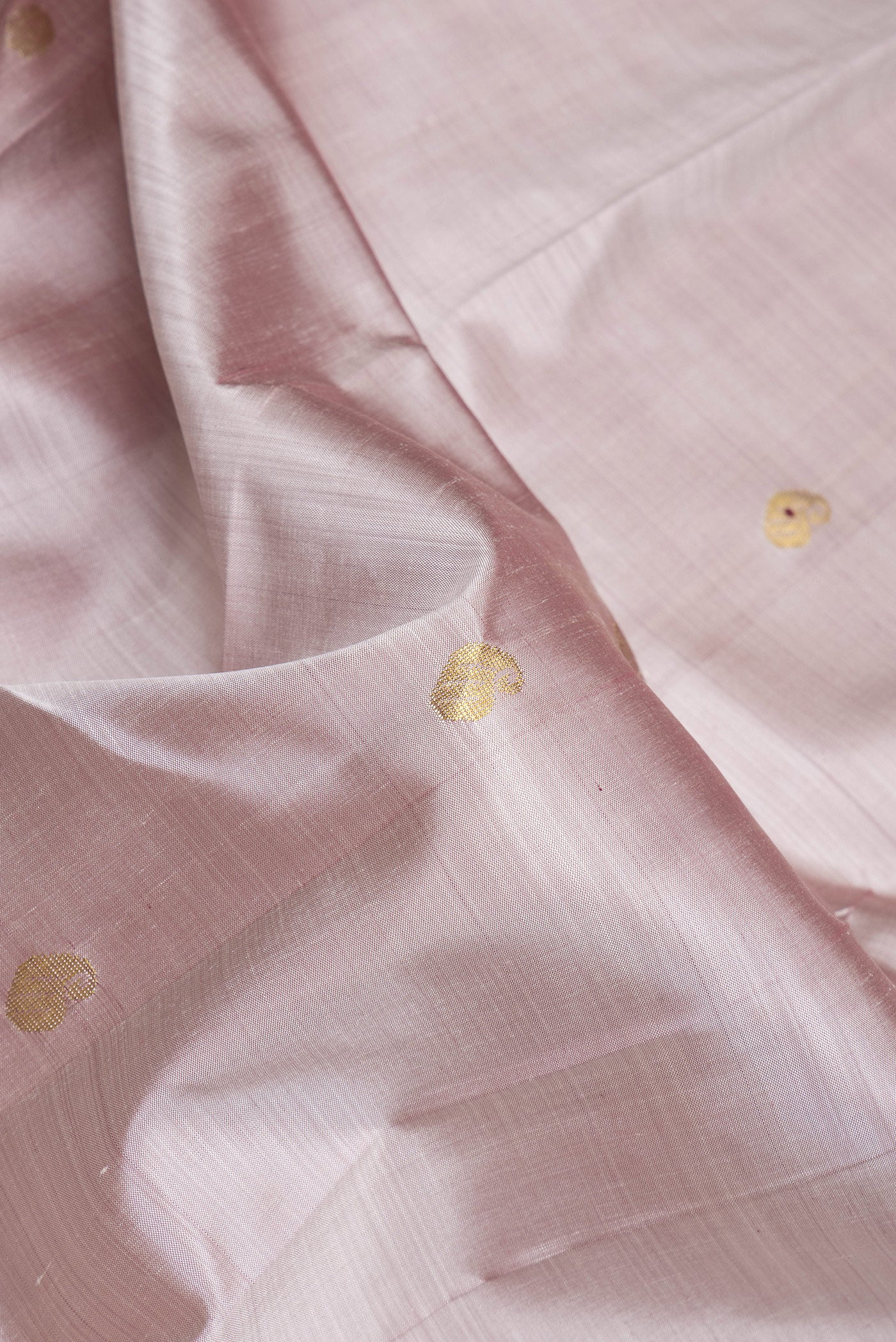 Close up of Rose Gold Dual Tone Kanjivaram Silk Saree with Zari Butta on the body and One Side Border.  displaying folds