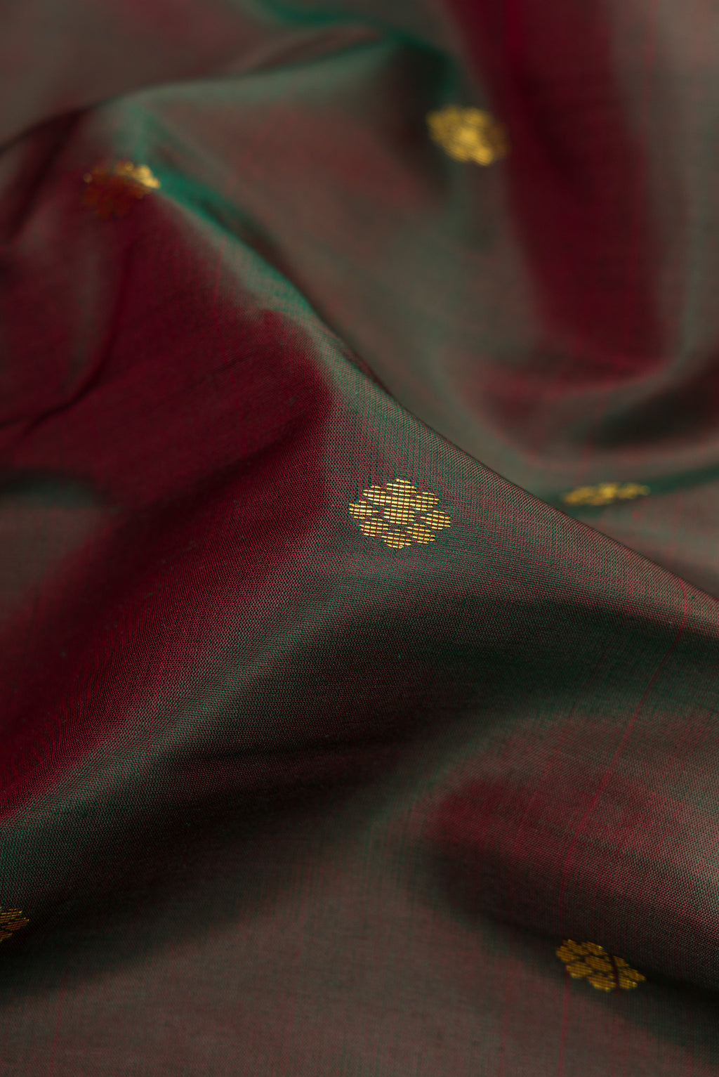 Close up of Maroon Dual Tone Kanchipuram Silk Saree with Zari Butta on the body and Zari Border.  displaying folds