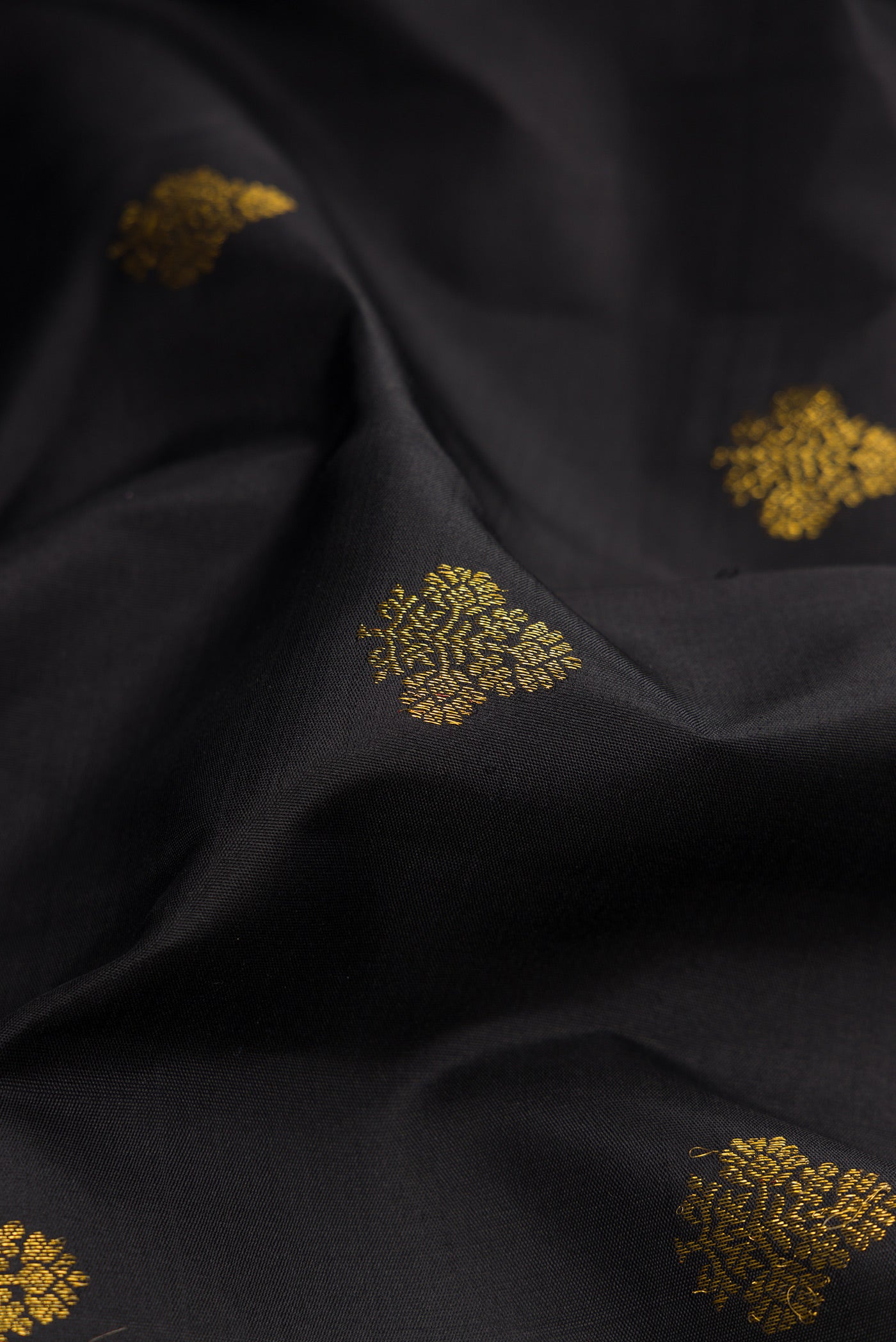 Close up of Black Kanjivaram Silk Saree with Zari Butta on the body and Zari Border.  displaying folds