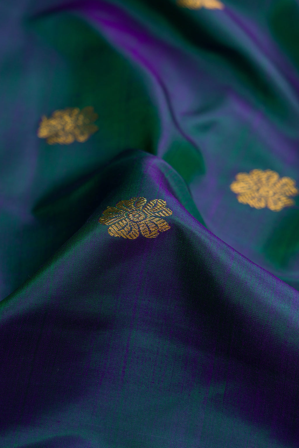 Close up of Peacock Blue Dual Tone Kanjivaram Silk Saree with Zari Butta on the body and Zari Border.  displaying folds