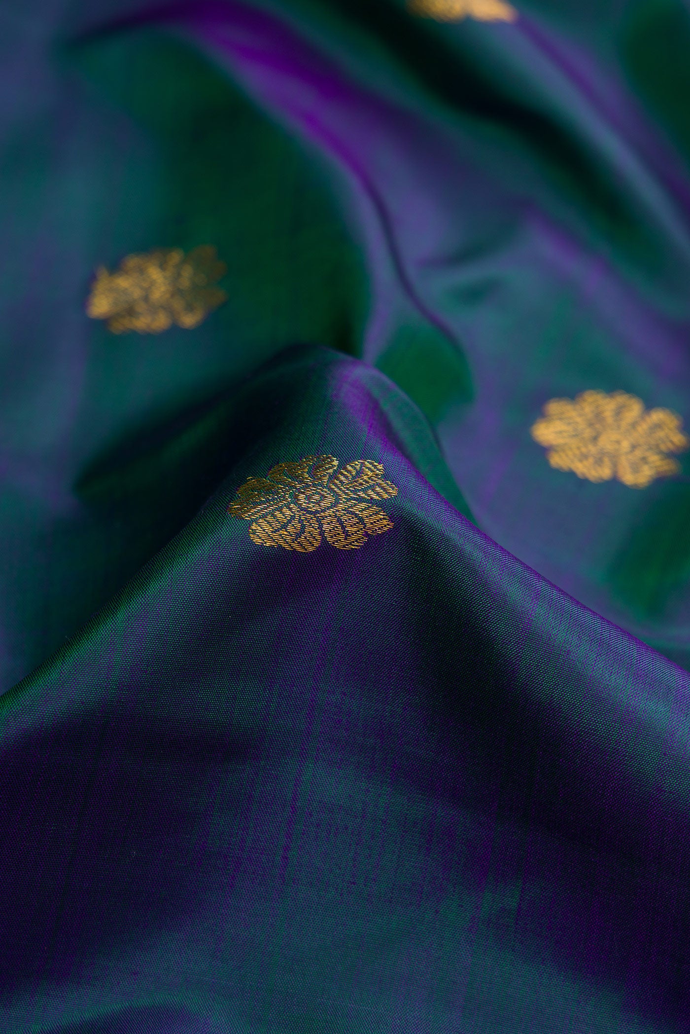 Close up of Peacock Blue Dual Tone Kanjivaram Silk Saree with Zari Butta on the body and Zari Border.  displaying folds