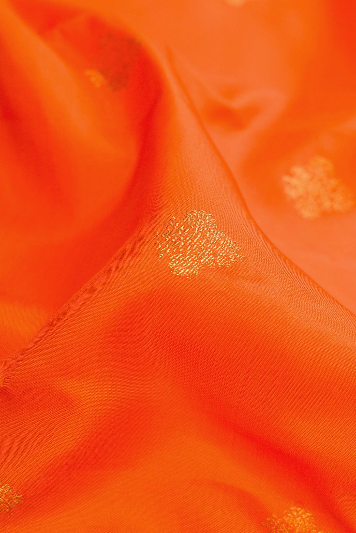 Close up of Orange Kanjivaram Silk Saree with Zari Butta on the body and Zari Border.  displaying folds