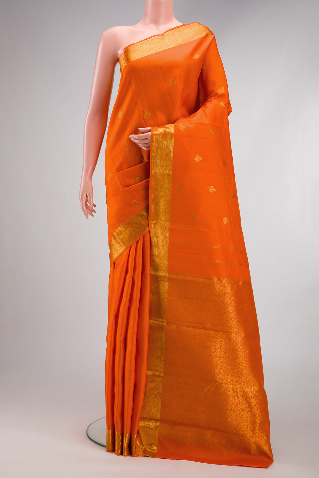 Orange Kanjivaram Silk Saree with Zari Butta on the body and Zari Border.  displayed on a mannequin