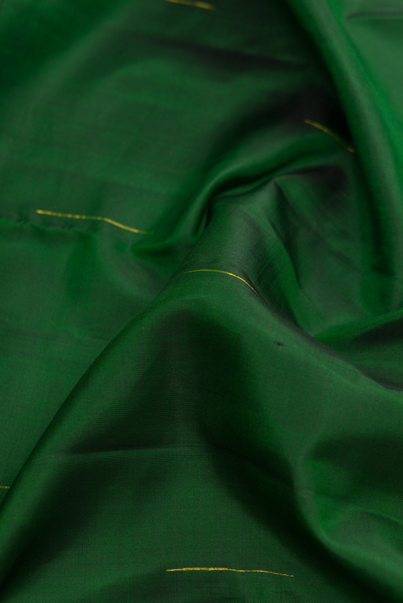 Close up of Bottle Green Kanchipuram Silk Saree with Zari Butta on the body and Zari Border.  displaying folds