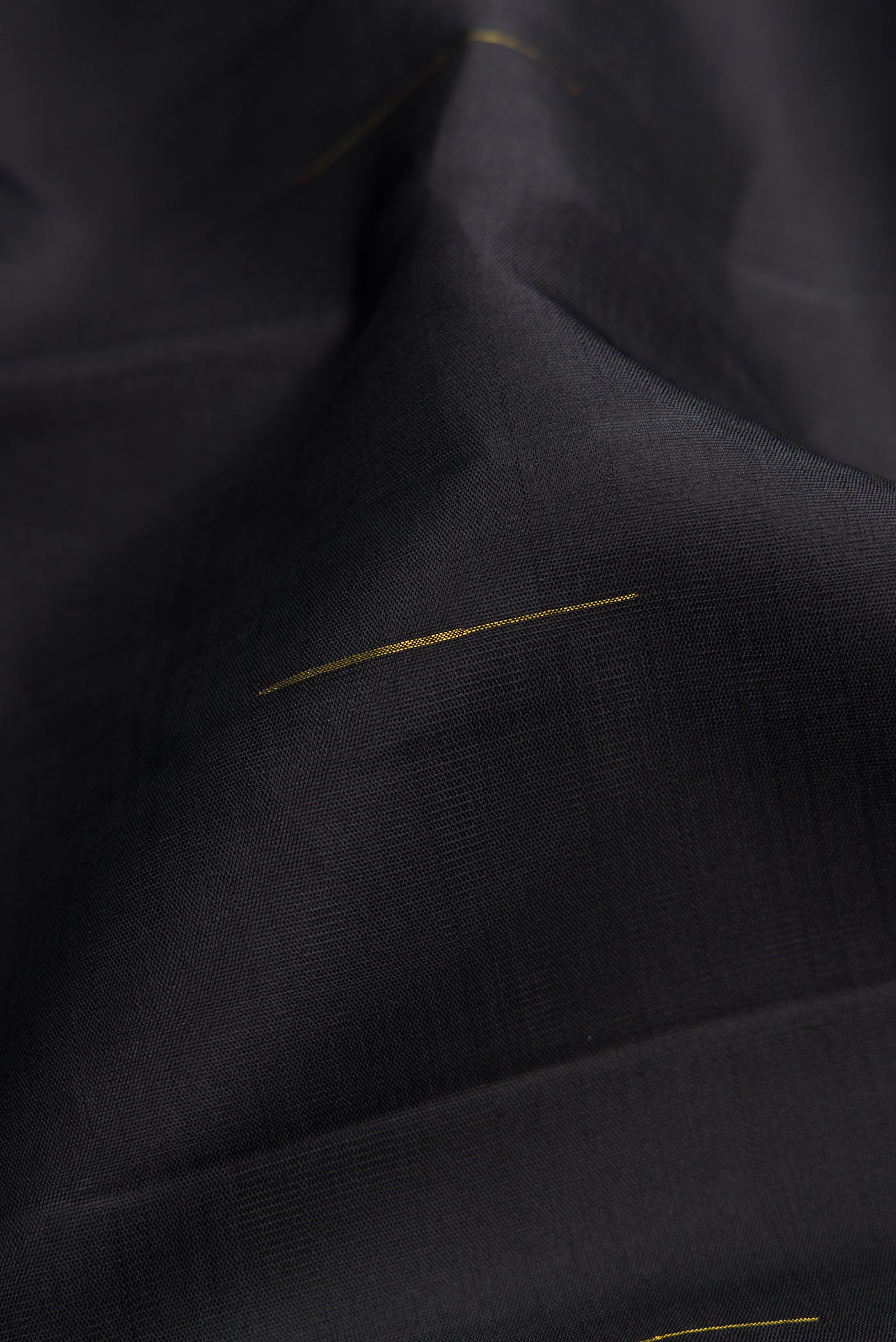 Close up of Black Kanchipuram Silk Saree with Zari Butta on the body and Zari Border.  displaying folds