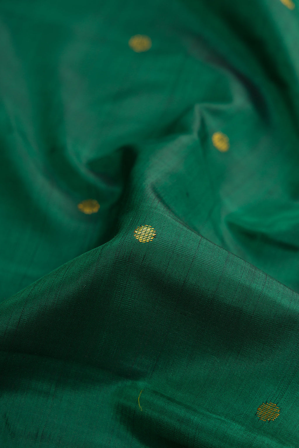 Close up of Green Dual Tone Kanjivaram Silk Saree with Zari Butta on the body and Zari Border.  displaying folds
