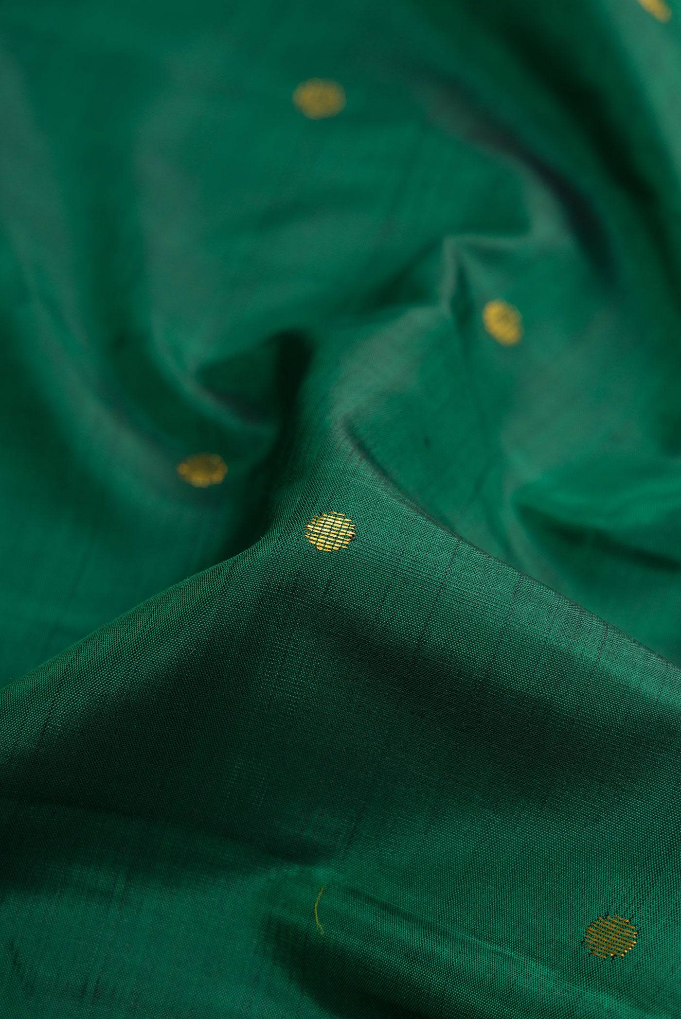 Close up of Green Dual Tone Kanjivaram Silk Saree with Zari Butta on the body and Zari Border.  displaying folds