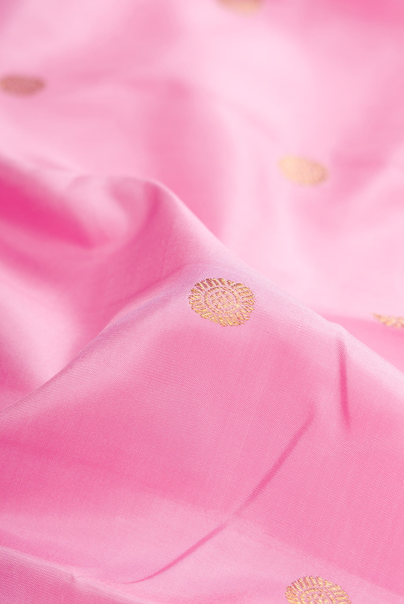 Close up of Pink Kanchipuram Silk Saree with Zari Butta on the body and Zari Border.  displaying folds