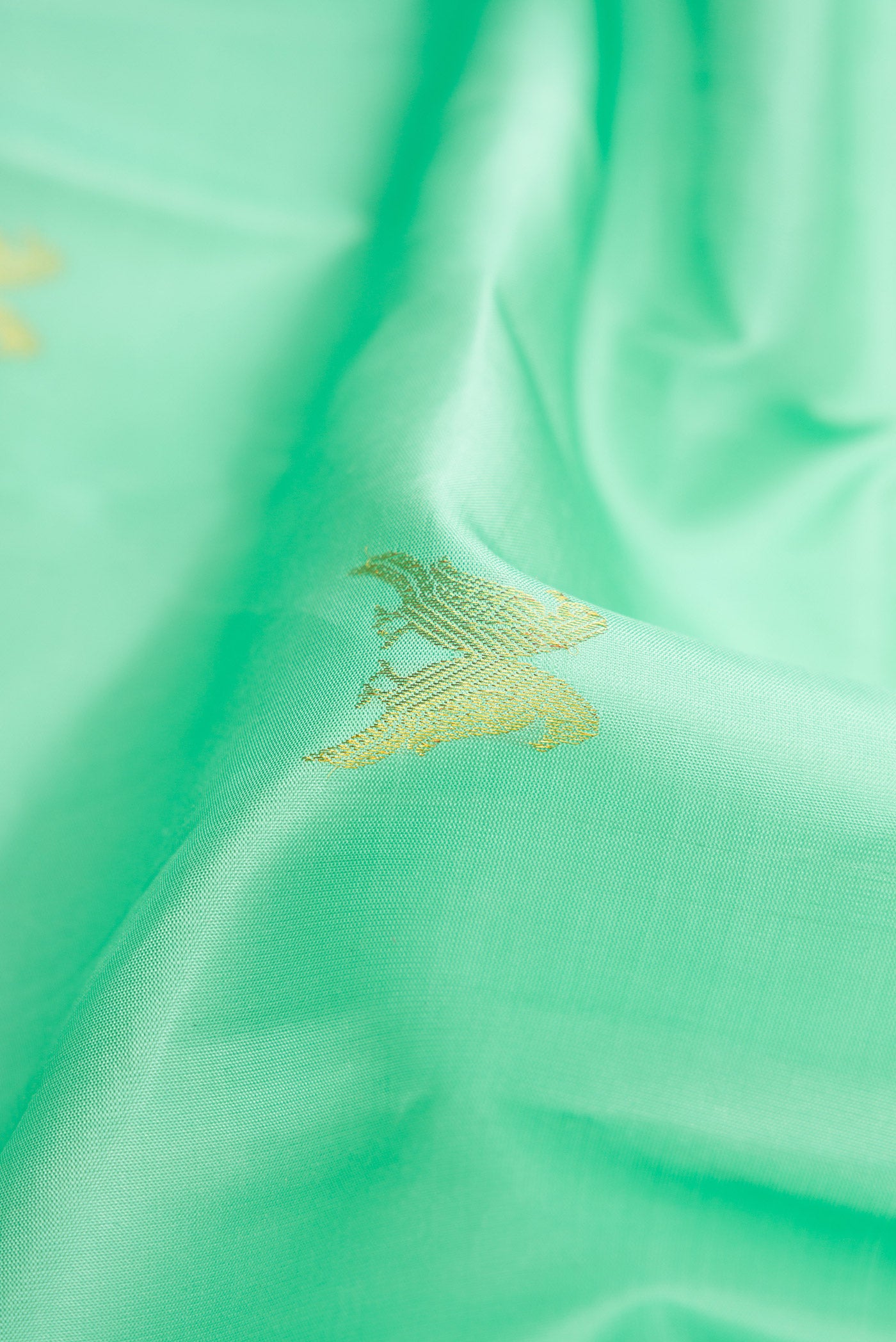 Close up of Sea Green Dual Tone Kanchipuram Silk Saree with Zari Butta on the body and Thin Zari Line.  displaying folds