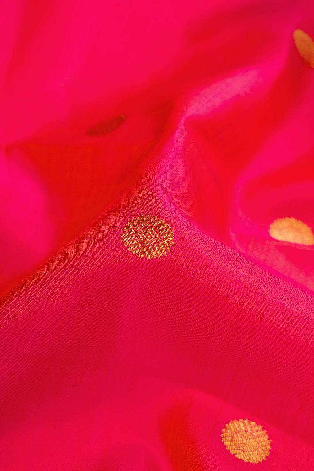 Close up of Coral Dual Tone Kanchipuram Silk Saree with Zari Butta on the body and Zari Border.  displaying folds