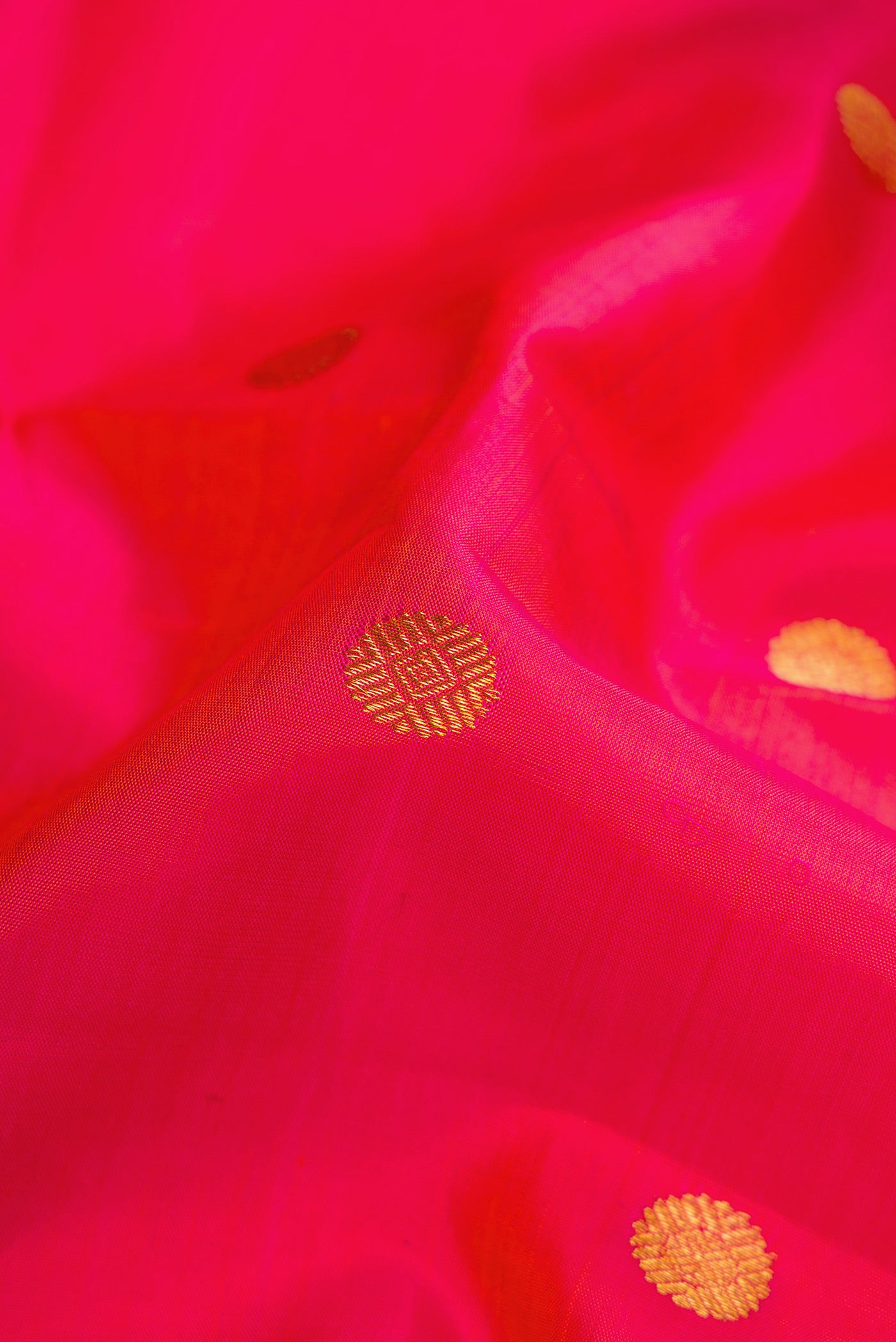 Close up of Coral Dual Tone Kanchipuram Silk Saree with Zari Butta on the body and Zari Border.  displaying folds