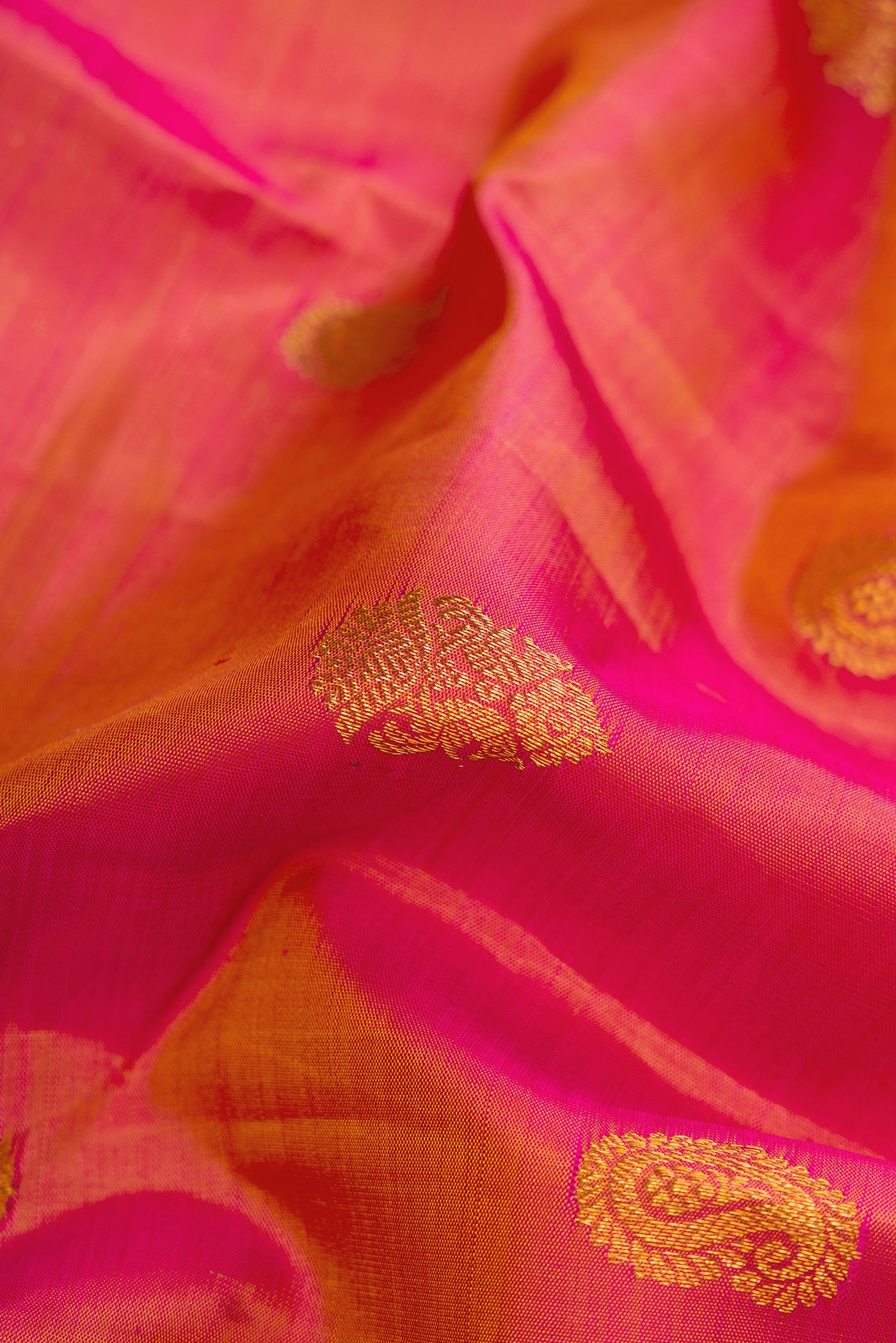 Close up of Orange Dual Tone Kanchipuram Silk Saree with Zari Butta on the body and Zari Border.  displaying folds