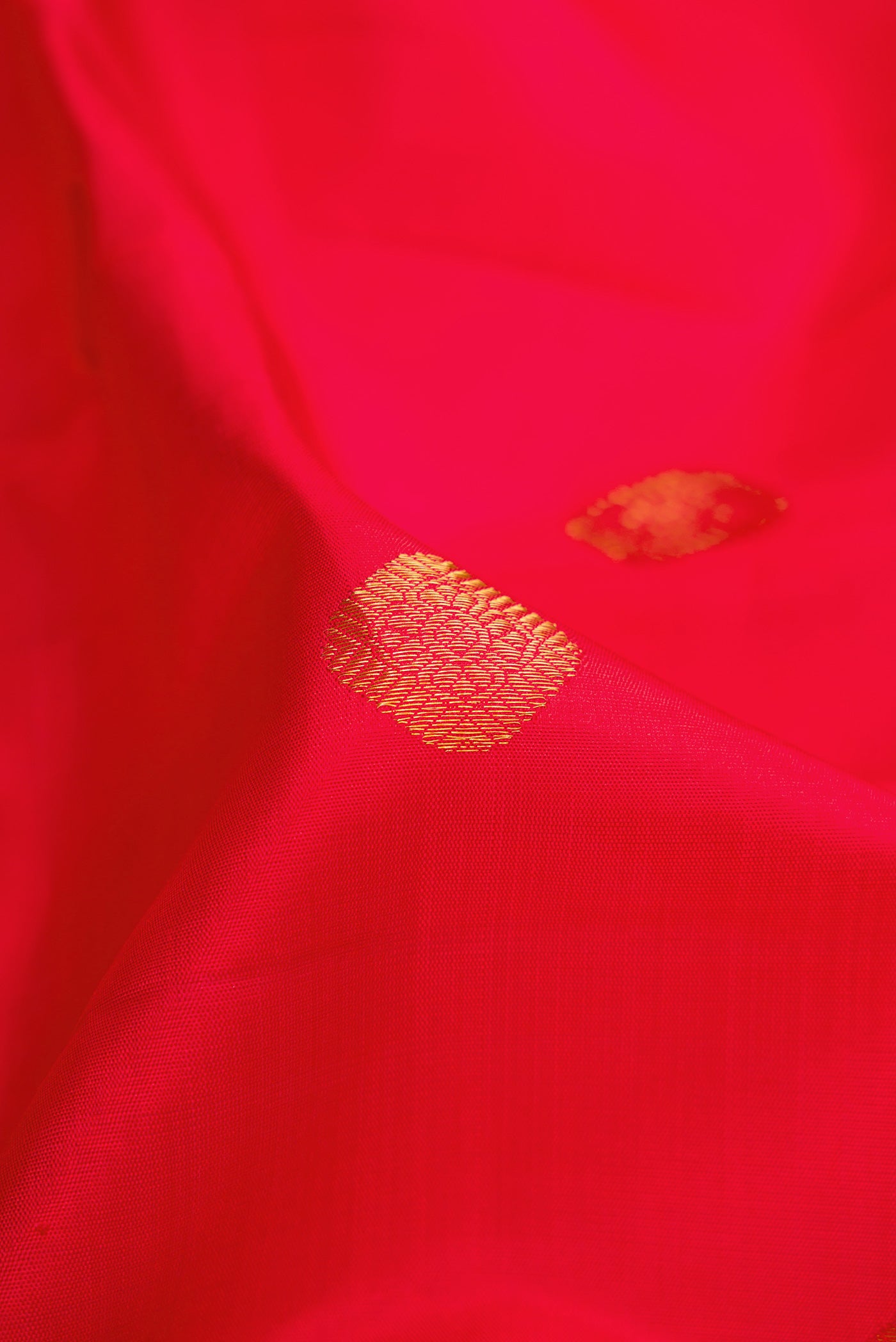 Close up of Red Dual Tone Kanchipuram Silk Saree with Zari Butta on the body and Zari Border.  displaying folds