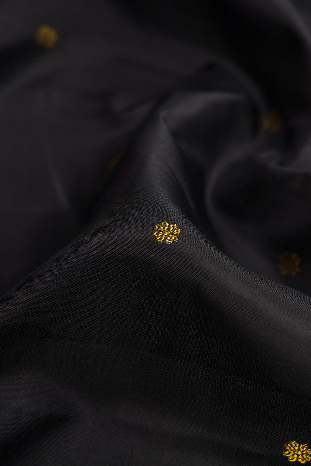 Close up of Black Dual Tone Soft Silk Saree with Zari Butta on the body and Fancy Border.  displaying folds